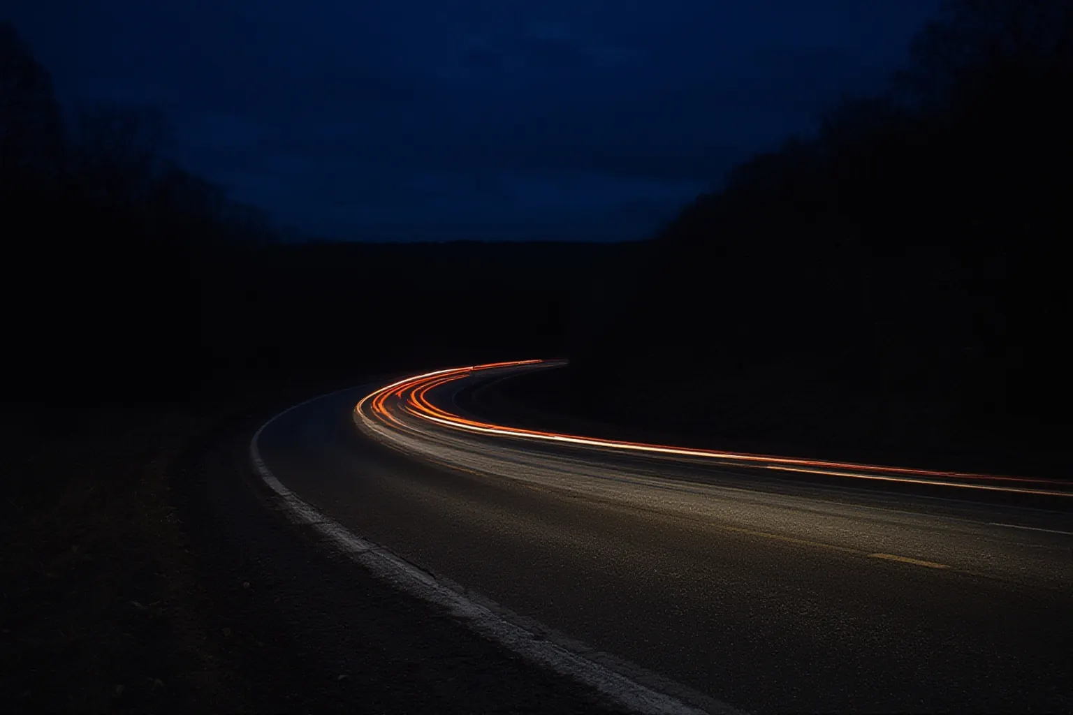 Red and white light trails on a curving highway at night