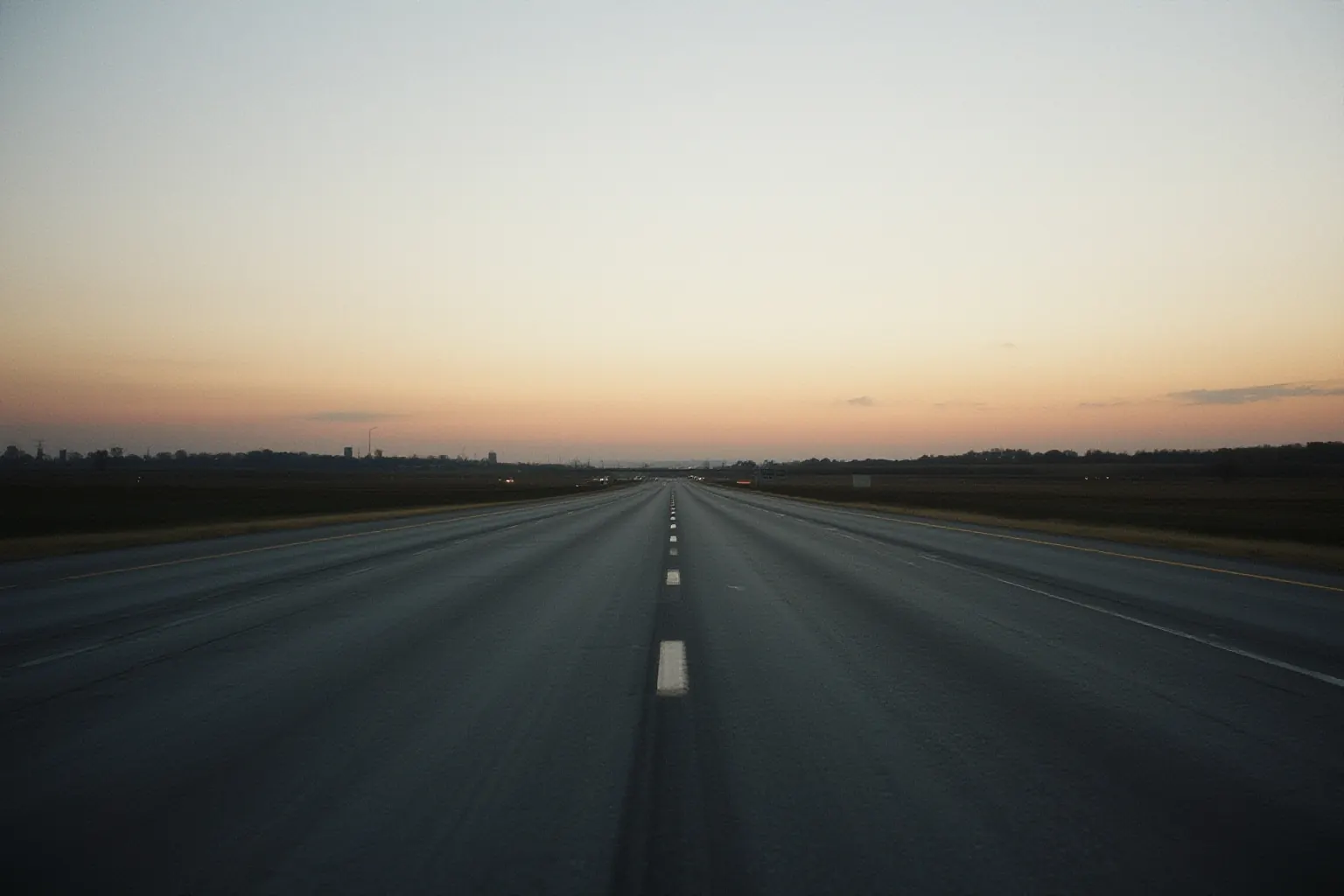 Highway lanes narrowing toward a distant horizon at dusk