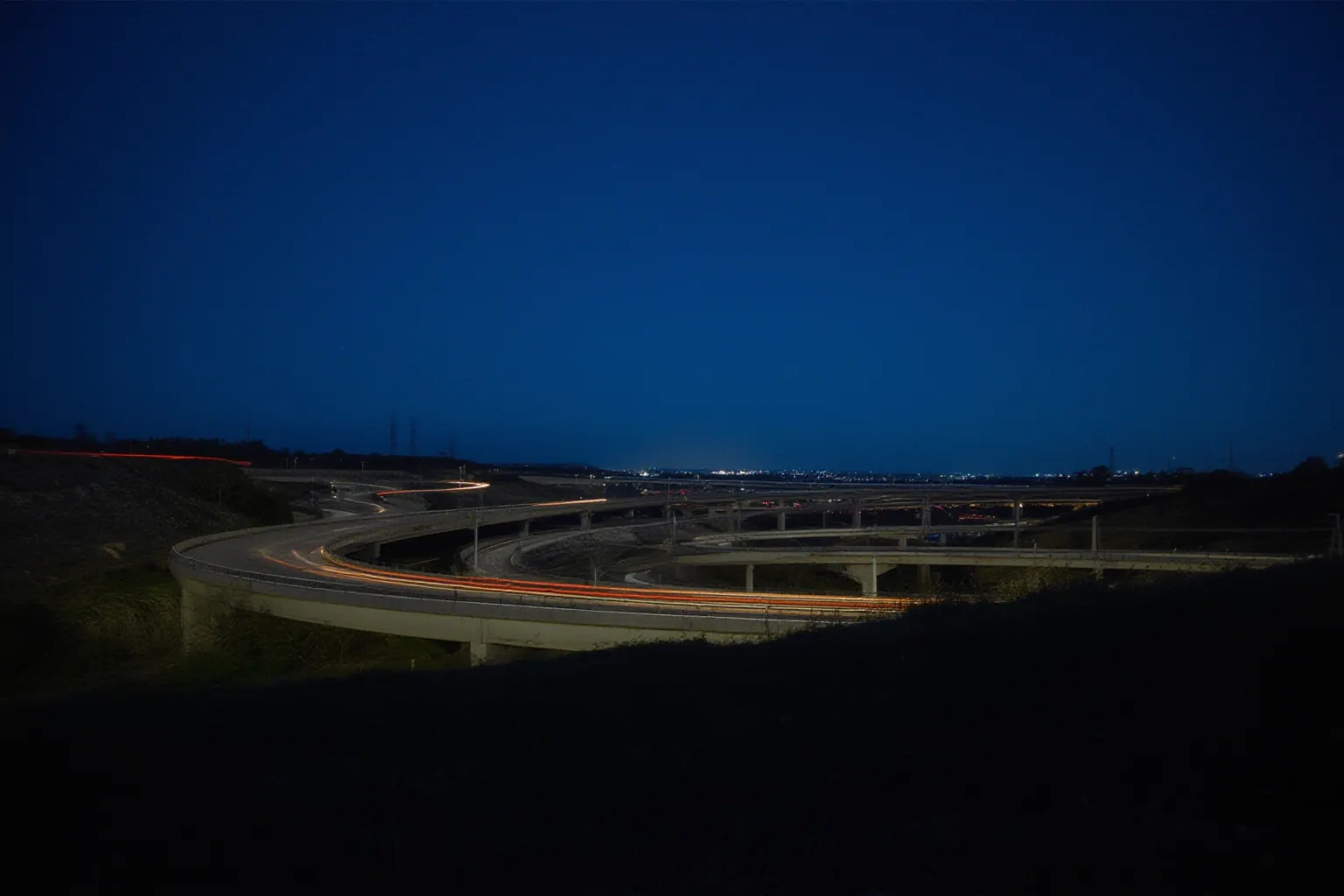 Looping highway interchange ramps at night with light trails